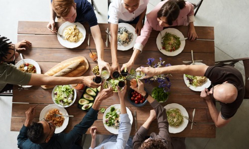 Overhead shot fo people at a table doing a cheer and about to eat food.