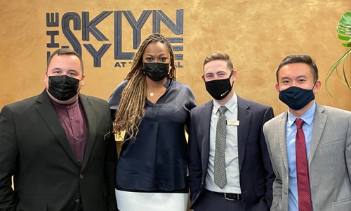 new team members in front of The Skylyne sign in office